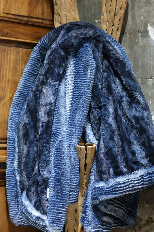 Blue textured blanket draped over a wooden chair against a rustic background